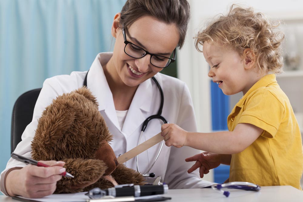 Doctor with child patient examining teddy bear